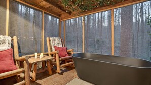 A wooden deck with a bathtub, two chairs, and a table. - Good Times cabin at Saluda Grade Cabins! (Saluda)