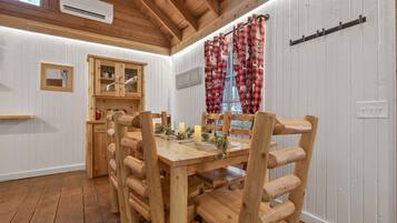 Une table de salle à manger en bois, avec des chaises, un buffet et une fenêtre ornée de rideaux à carreaux rouges et noirs.
