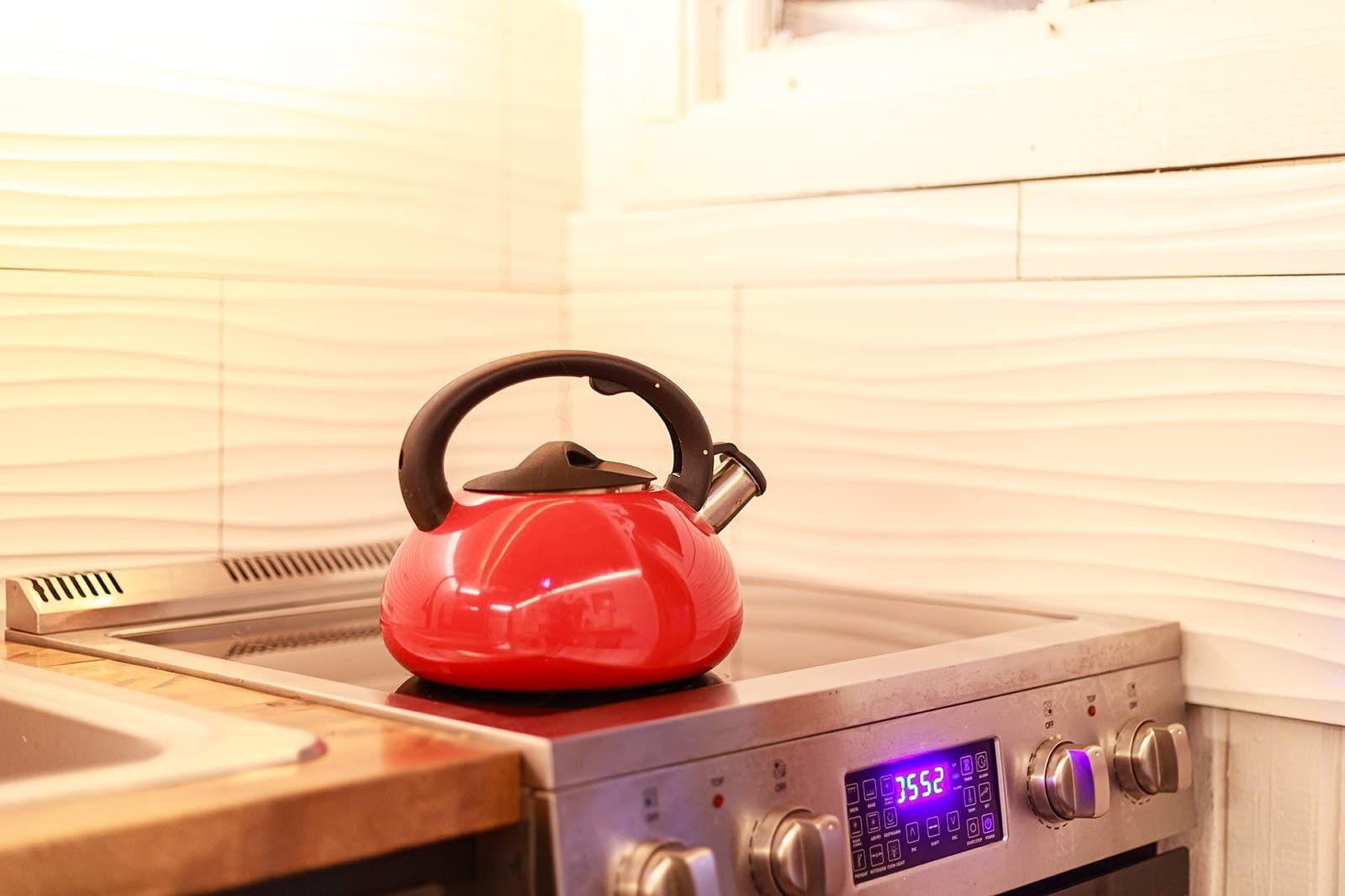 A red kettle on a stove with a digital display.