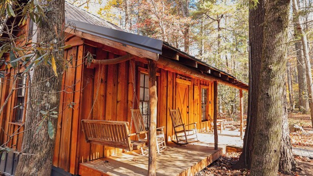 A rustic cabin with a porch, wooden chairs, and a small deck. - Ever After Escape at Saluda Grade Cabins! (Saluda)