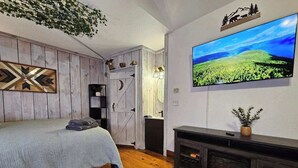 Un dormitorio con cama, televisión, chimenea y pared de madera.