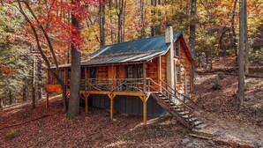A rustic cabin with a wooden deck and a staircase leading to the entrance. - Lover's Nest at Saluda Grade Cabins! (Saluda)