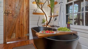 A rustic kitchen with a wooden door, a black sink, and a wooden countertop with food and wine. - Lover's Nest at Saluda Grade Cabins! (Saluda)