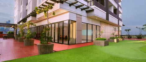 A modern building with large glass windows, a flat roof, and a well-maintained green lawn.