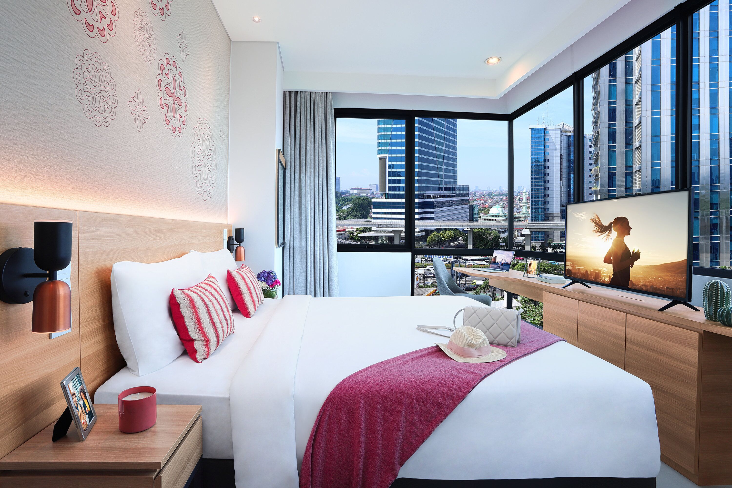 A modern hotel room with a large bed, a TV, and a city view.