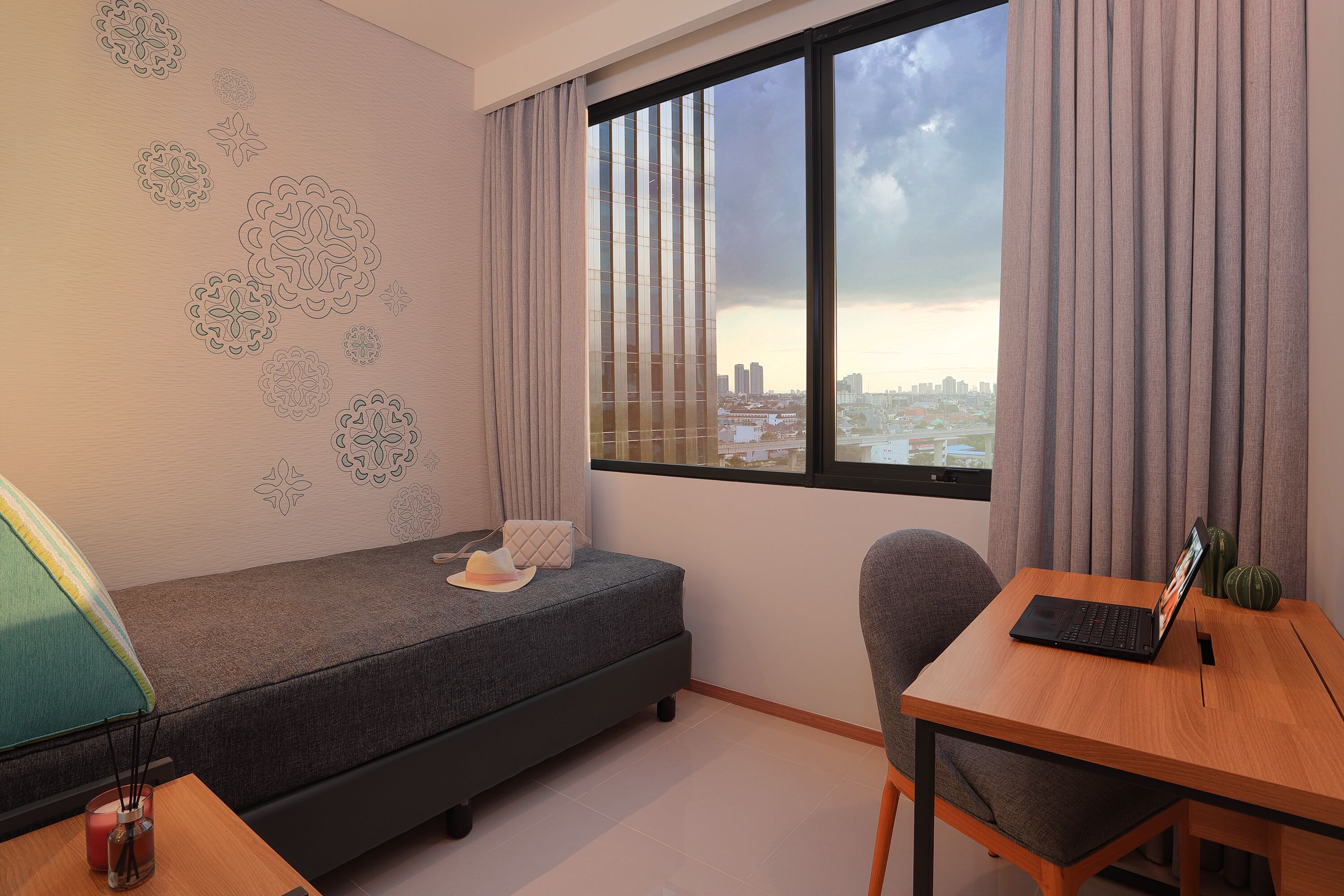 A small room with a bed, a desk, and a window with a city view.
