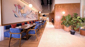 Een restaurant met een lange toonbank, blauwe gestoffeerde zithoeken en een grote muurschildering.