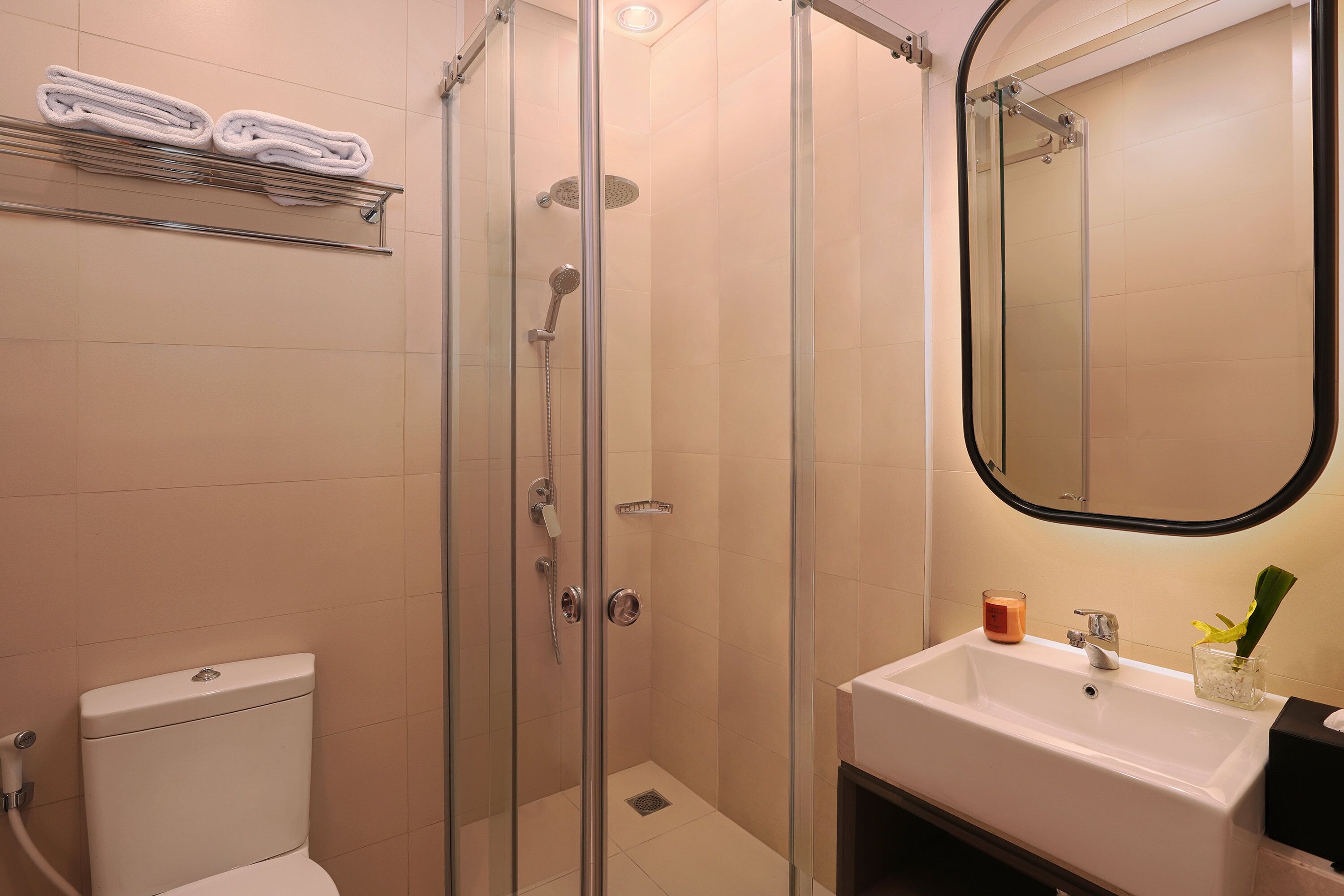 Ein modernes Badezimmer mit einer gläsernen Duschkabine, einem weißen Waschbecken und einer Toilette.