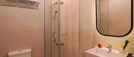 Ein modernes Badezimmer mit einer gläsernen Duschkabine, einem weißen Waschbecken und einer Toilette.