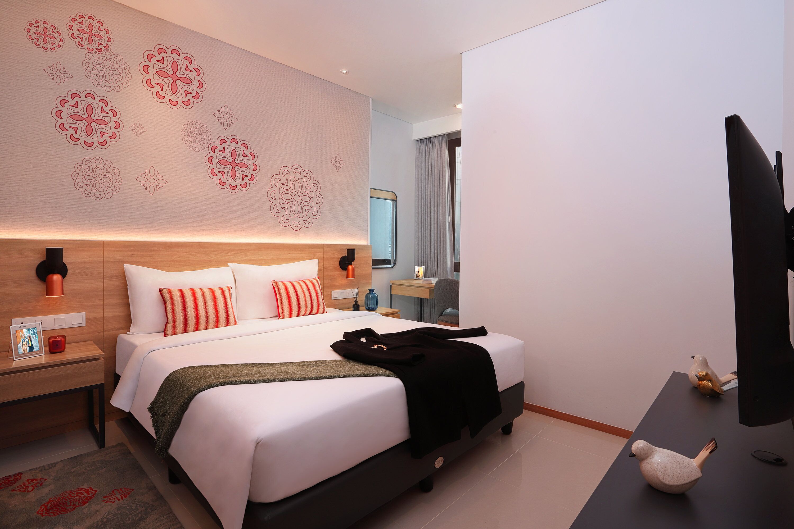 A modern hotel room with a large bed, a desk, and a television.