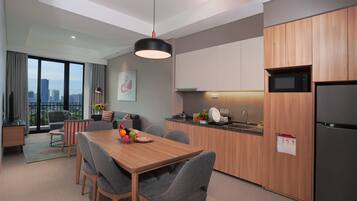 Una cocina moderna con armarios de madera, un refrigerador de acero inoxidable y una zona de comedor con una mesa de madera y sillas grises.
