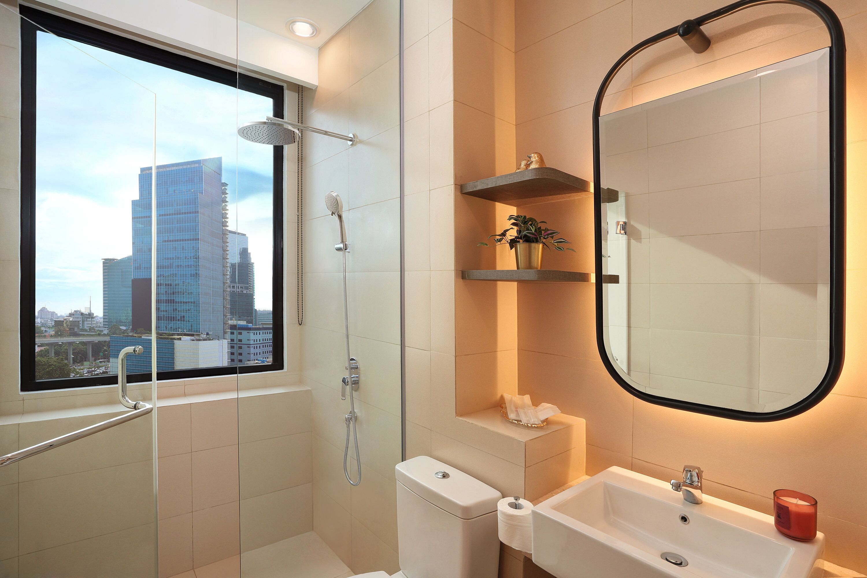 A modern bathroom with a large window, a shower, a toilet, and a sink.