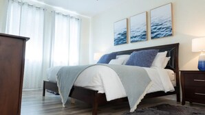 A bedroom with a bed, a dresser, and a nightstand. There are three framed pictures on the wall above the bed. - Beautiful Luxury Condo (Davenport)