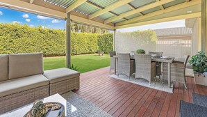 Un patio techado al aire libre con un sofá, una mesa de comedor y sillas.