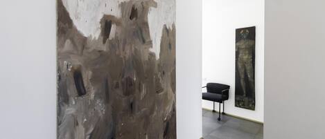 An art gallery with a large abstract painting and a smaller piece on the wall.
