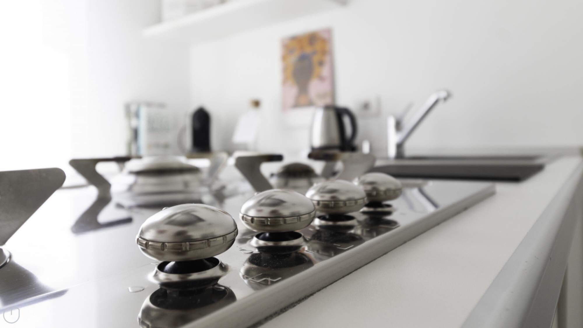 A kitchen with a modern stove, a coffee maker, and a kettle on the counter.