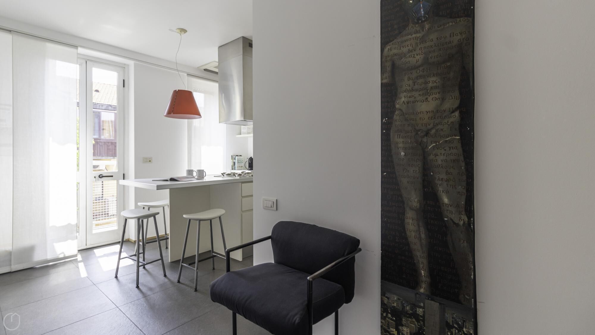 A modern kitchen with a white countertop, a red pendant light, and a black chair.