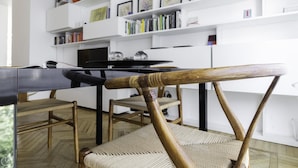 A dining area with a black table, wooden chairs, and a white bookshelf in the background. - Italianway Comfort - Palestrina 31 (Milan)