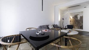 A modern living room with a black dining table, wicker chairs, a grey sofa, and a large abstract painting on the wall. - Italianway Comfort - Palestrina 31 (Milan)