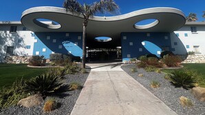 Ein modernes Gebäude mit einem einzigartigen architektonischen Design, das sich durch kreisförmige Aussparungen und eine blaue und weiße Farbgebung auszeichnet.