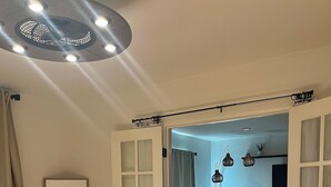 Ein Schlafzimmer mit einem Bett, einem Spiegel und einer Tür zu einem Wohnbereich mit Sofa und Fernseher.