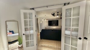 Una habitación con un espejo grande, un televisor y un sofá de color oscuro.