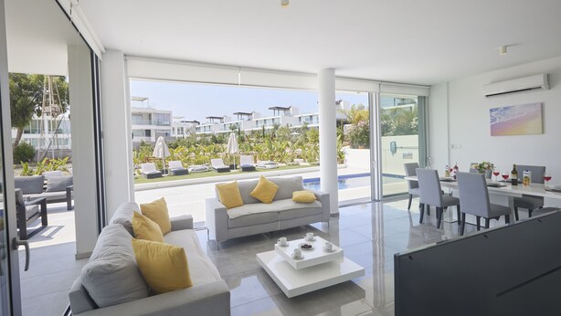 Uma sala de estar moderna com sofá, mesa de centro e área de jantar com cadeiras e uma mesa.