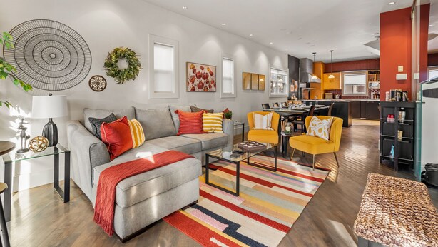 Un salon moderne avec un canapé gris, un fauteuil jaune et une table basse.