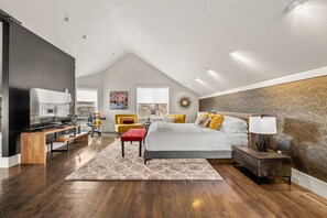 Un dormitorio moderno con una cama grande, televisor, escritorio y silla.
