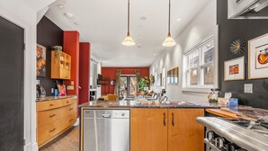 Une cuisine moderne avec des meubles en bois, des appareils électroménagers en acier inoxydable et des luminaires suspendus.