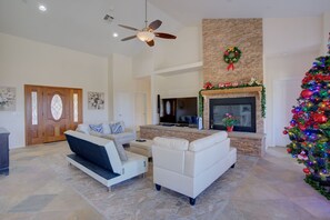 A spacious living room with a fireplace, a large TV, and a Christmas tree.