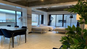 Una habitación moderna con un ventanal grande, un escritorio con sillas y dos camas individuales.
