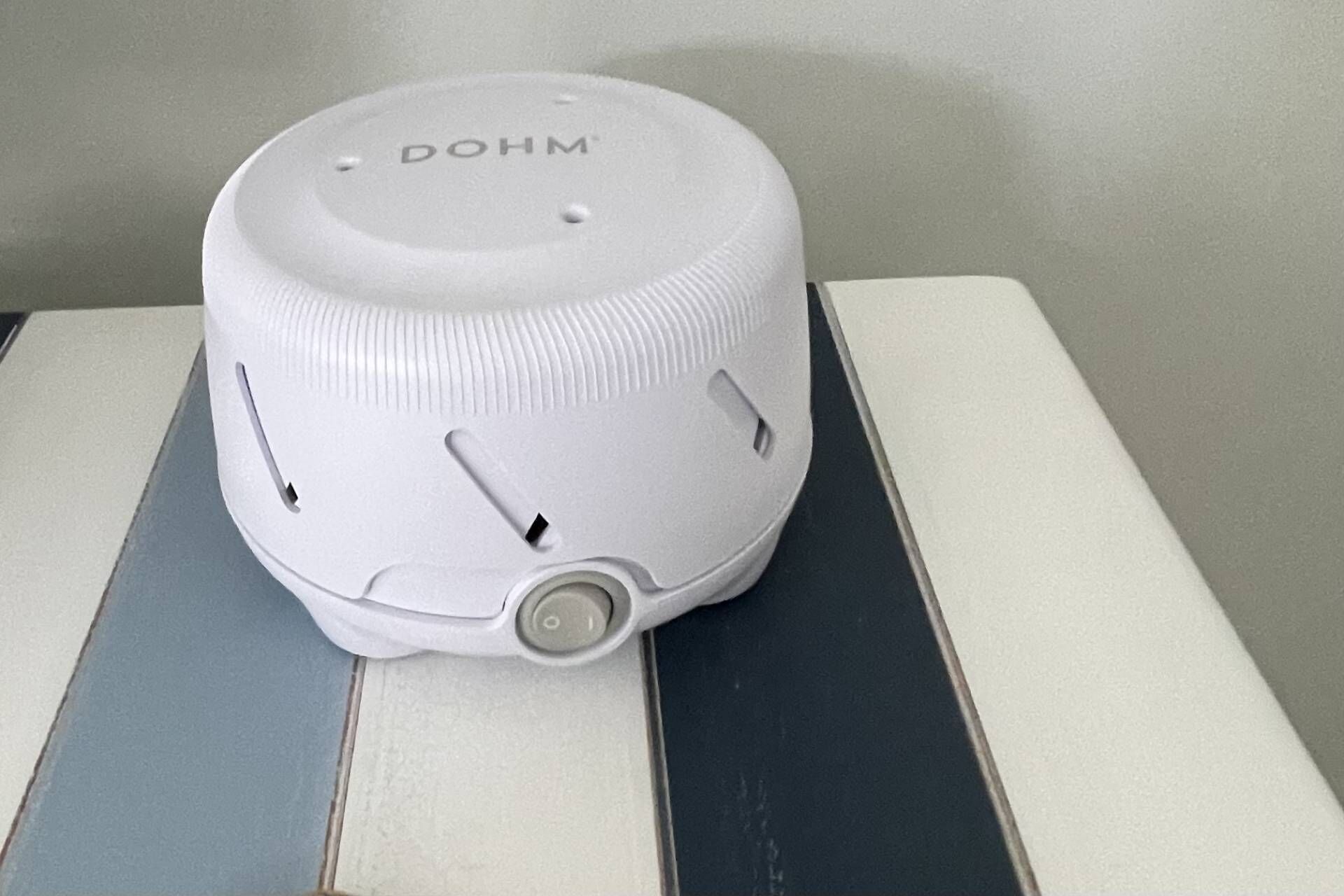 Un appareil cylindrique blanc, sur lequel est inscrit le mot « DOHM », est posé sur une table à motifs rayés.