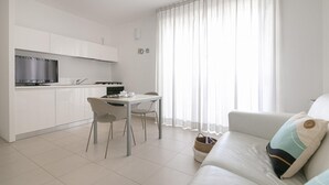 A modern, minimalist apartment with a kitchen, dining area, and living room.