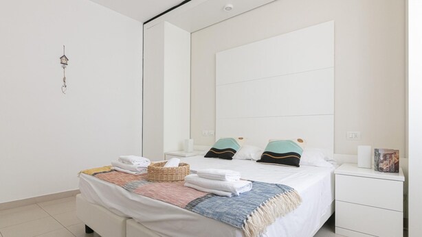 A modern bedroom with a large bed, a bedside table, a nightstand, and a mirror.