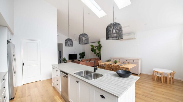 A modern kitchen with a central island, stainless steel sink, and pendant lights.