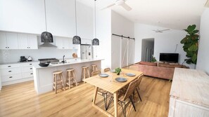 A modern kitchen with white cabinets, a central island with stools, and pendant lighting. - Surfleet Serenity is a coastal duplex (Kiama)