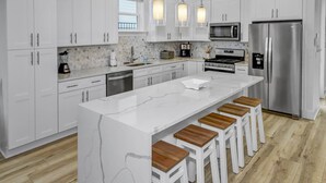A modern kitchen with white cabinetry, a central island with stools, stainless steel appliances, and pendant lighting. - Private *Heated Pool | Free Golf Cart | New Home | Patio Area | 5 Outdoor Spaces | Game Table (Santa Rosa Beach)