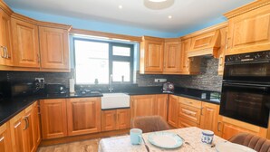 Una cocina con armarios de madera, encimera negra y una mesa para dos personas.