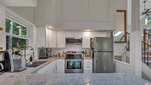 A modern kitchen with white cabinets, stainless steel appliances, and a granite countertop.
