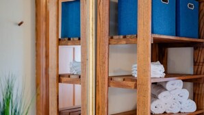 A wooden shelf with blue storage boxes and neatly folded white towels.