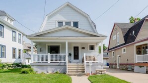A two-story house with a front porch, a small front yard, and a driveway.
