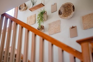 A staircase with wooden railings and a wall decorated with woven baskets and a clipboard.