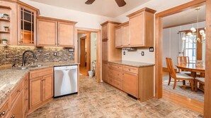 A kitchen with wooden cabinets, a dishwasher, and a dining area with a table and chairs.