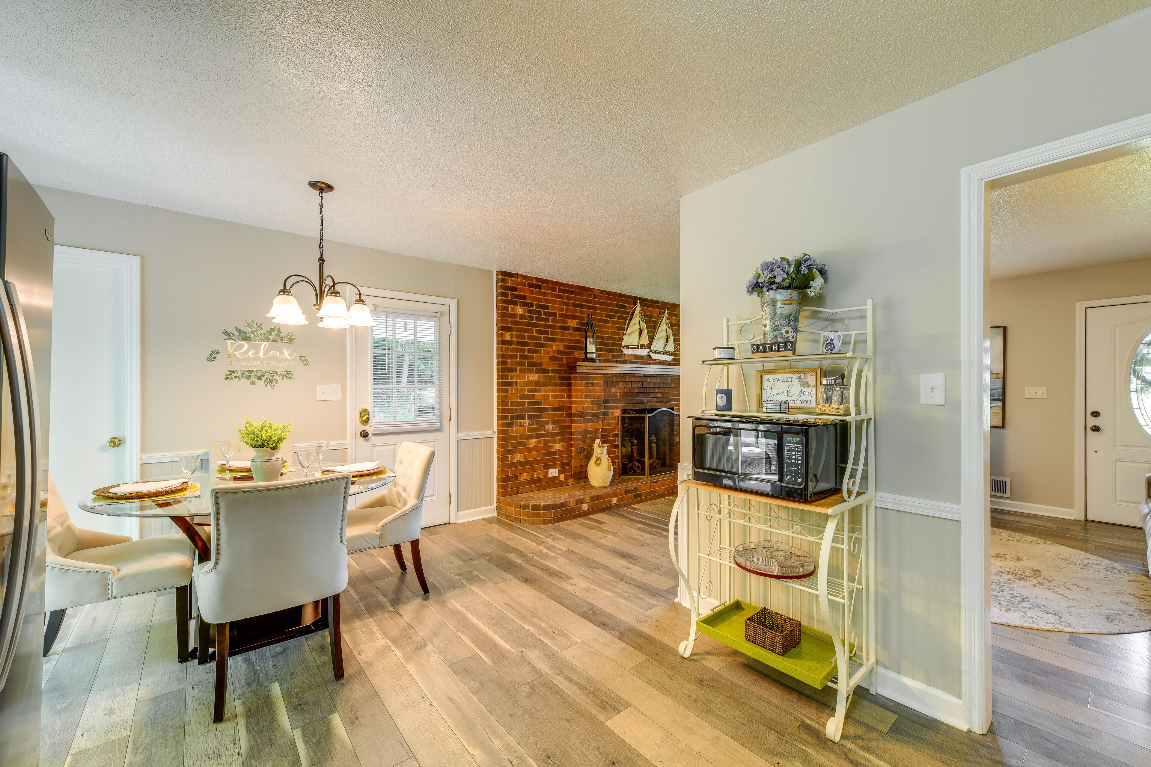 A modern kitchen with a brick backsplash, a dining area with a round table and chairs, and a built-in microwave shelf.