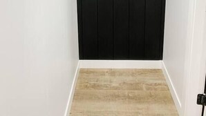 Une porte noire fermée, dotée de trois poignées en bois et surmontant un plancher en bois.