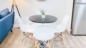 Une cuisine moderne avec une table de salle à manger ronde, des chaises blanches, un canapé bleu, une lampe sur pied et un élément décoratif mural.