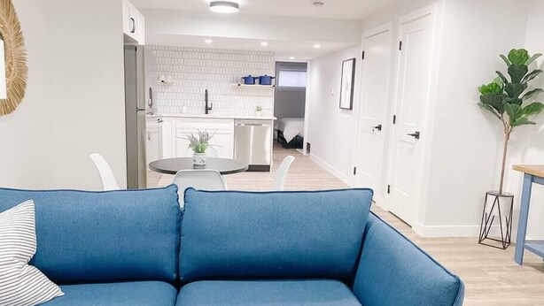 Un salon moderne avec un canapé bleu, une table à manger avec des chaises, et une cuisine en arrière-plan.