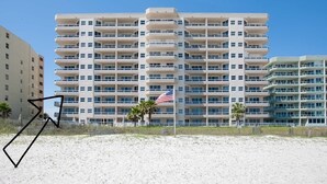 A multi-story hotel with balconies, located near a beach.