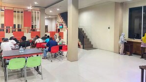 Un'ampia area interna con diversi tavoli e sedie, una scala e un'ampia finestra.